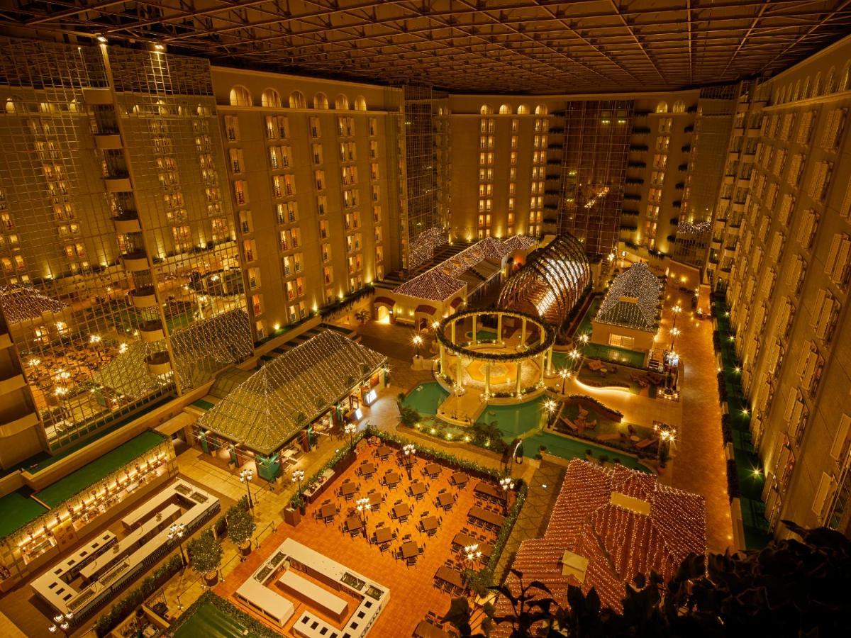 Hotel Grand Nikko Tokyo Bay Maihama Urayasu Exterior foto The photo shows a large, illuminated atrium of a hotel or resort complex. Several floors of what appear to be guest rooms or apartments surround the central area. The atrium contains a variety of amenities, including a pool or water feature, landscap