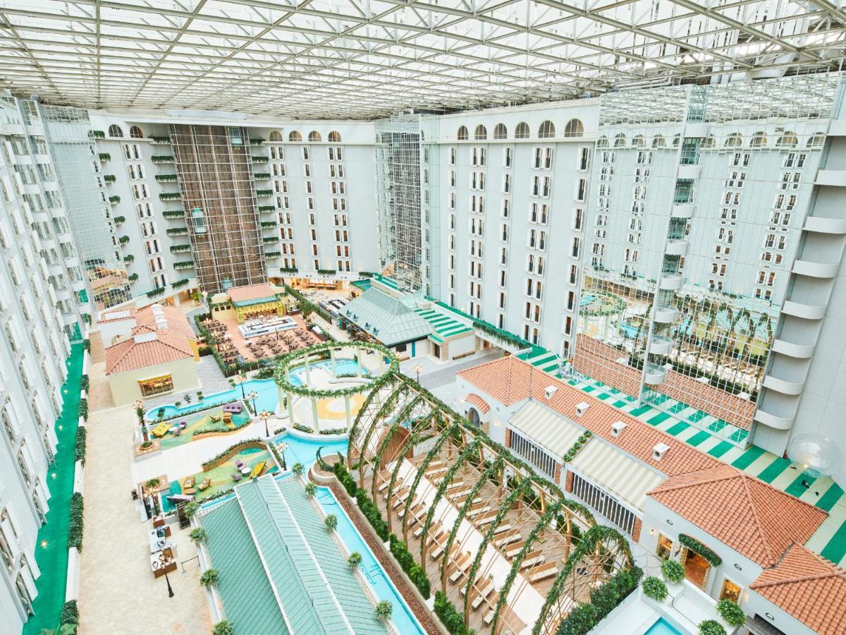 Hotel Grand Nikko Tokyo Bay Maihama Urayasu Exterior foto The photo shows a large indoor space, likely a hotel or resort atrium. The area features multiple levels of buildings surrounding a central courtyard. This courtyard includes various amenities such as pools, landscaped gardens, and recreational areas