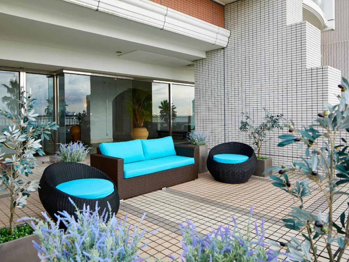 Hotel Grand Nikko Tokyo Bay Maihama Urayasu Exterior foto The image shows a stylish outdoor seating area. There is a brown couch with turquoise cushions, complemented by two matching round chairs nearby. The seating is arranged on a tiled patio, which is bordered by planters featuring lavender flowers and g