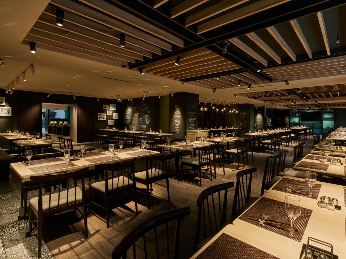 Hotel Grand Nikko Tokyo Bay Maihama Urayasu Exterior foto The photo shows the interior of a modern restaurant. The space features a spacious dining area with several long tables arranged in rows. Each table is set with dining utensils, plates, and glasses, indicating readiness for patrons. The lighting is s
