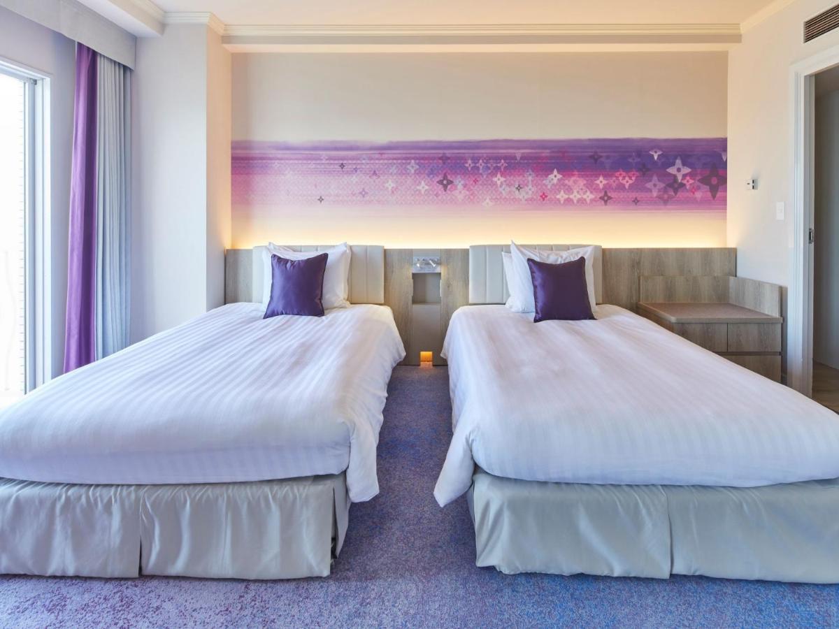 Hotel Grand Nikko Tokyo Bay Maihama Urayasu Exterior foto The photo shows a hotel room featuring two twin beds with white bedding and purple accent pillows. The beds are positioned next to each other, with a light-colored headboard. Behind the beds, there is a decorative wall with a gradient of purple hues.