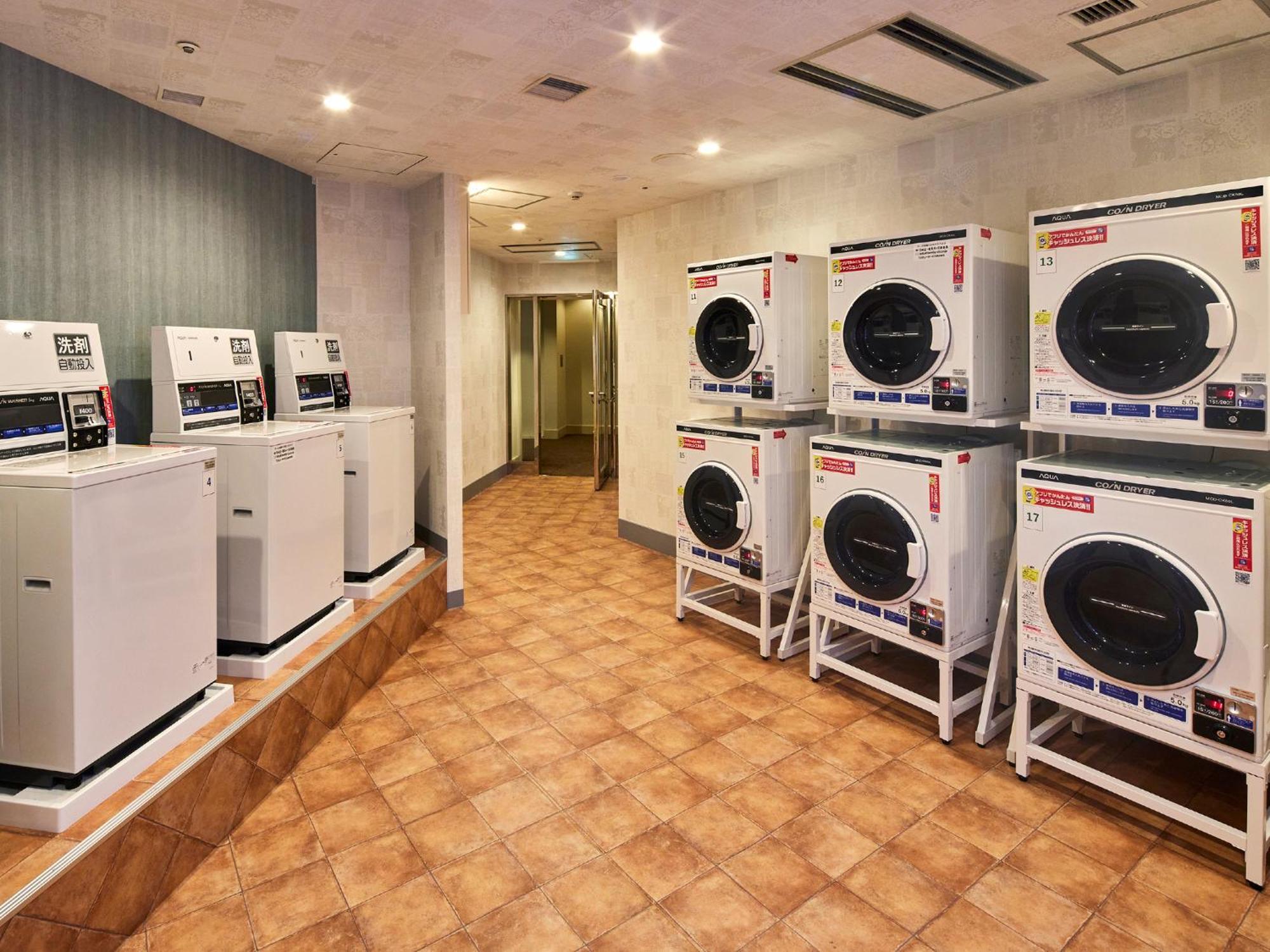 Hotel Grand Nikko Tokyo Bay Maihama Urayasu Exterior foto The photo shows a laundry room with several washing machines and dryers. On the left side, there are five white washing machines, and on the right side, there are four dryers. The machines are arranged in a clean, tiled space with a neutral-colored w